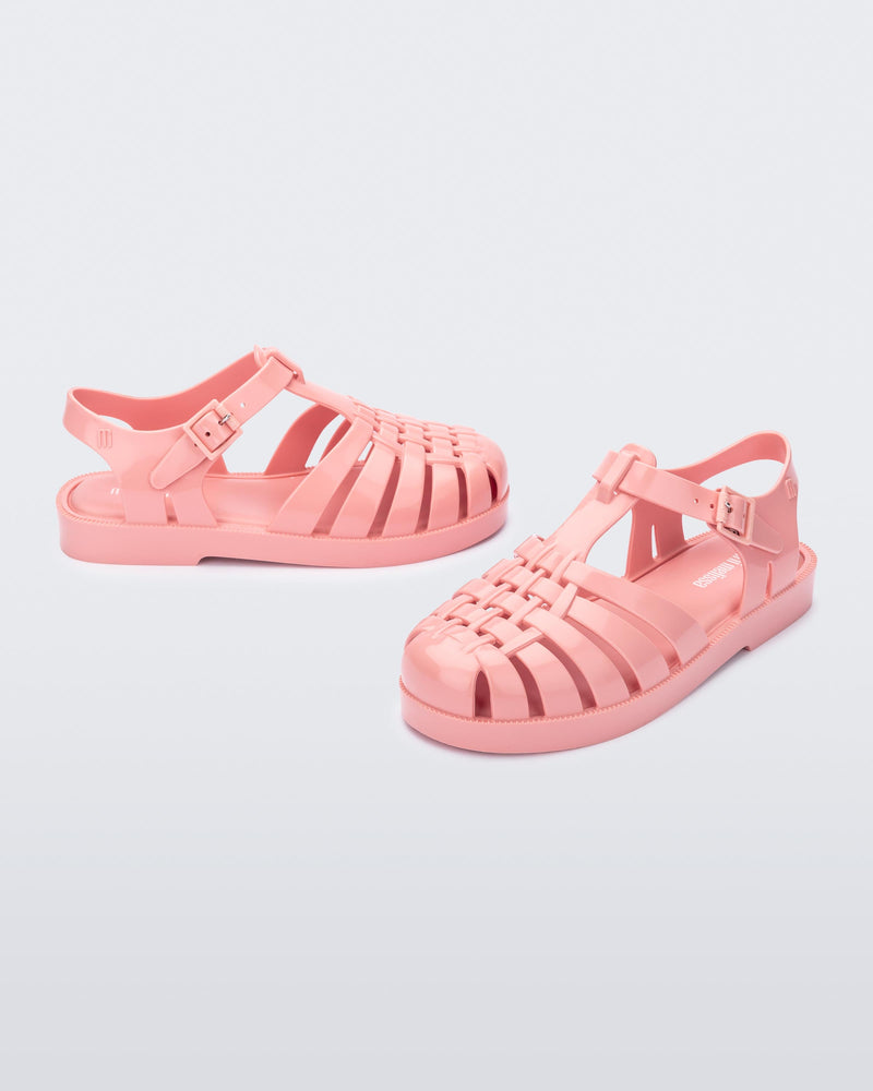 Side and angled view of a pair of light pink kids Possession sandals.
