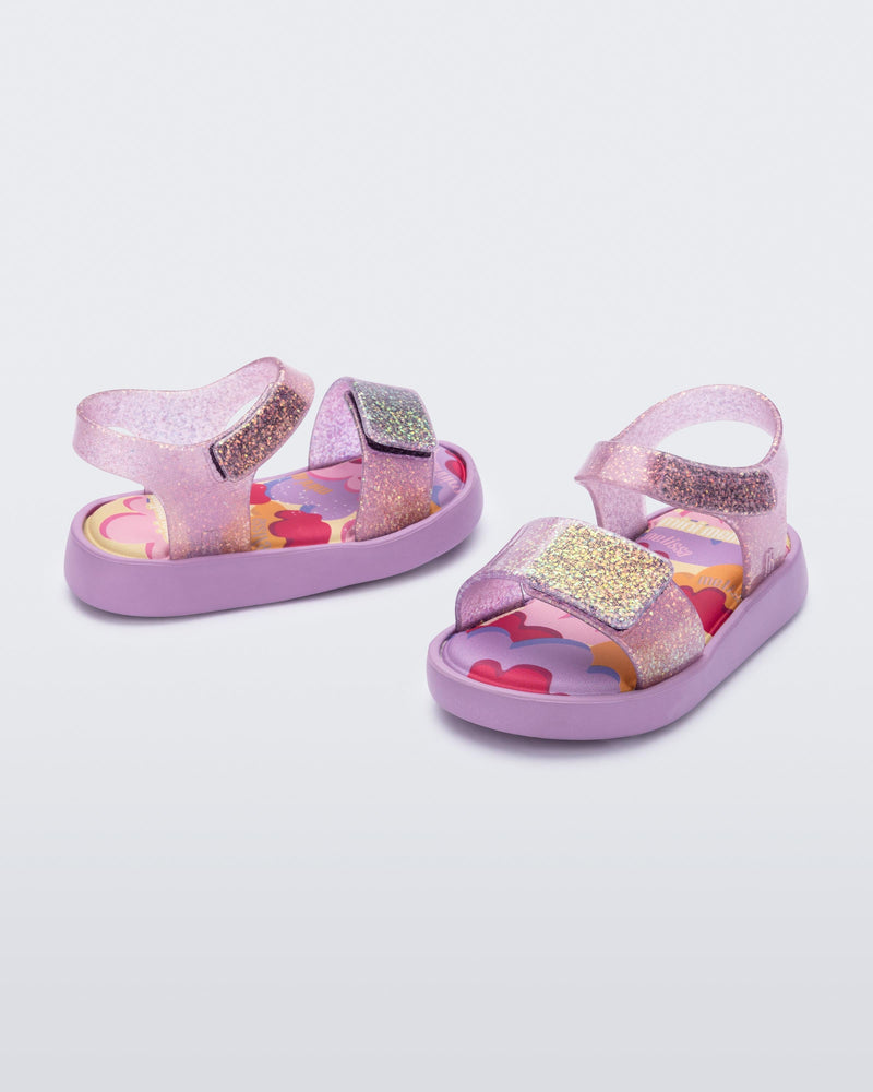 Angled view of a pair of glitter lilac baby Jump sandals