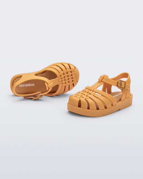 Top and side angled view of a pair of matte caramel Possession baby fisherman sandals.