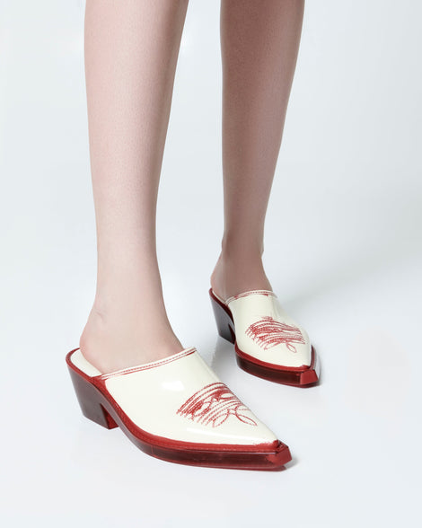 Model's legs wearing a pair of beige with red heel and accents Texas Mule heels