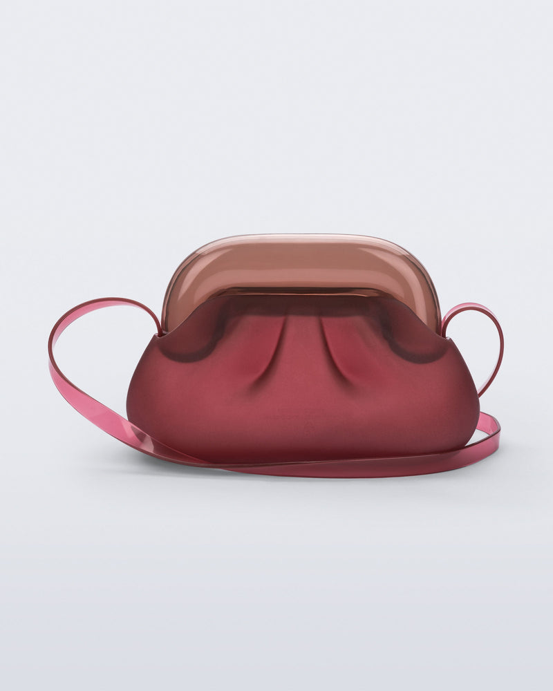 Back view of a small red bag with clear brown clutch and long strap
