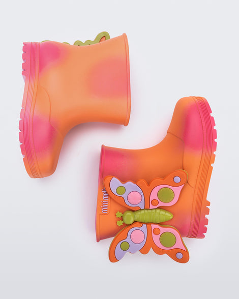 side view of a pair of orange with pink splotches Welly Wonderland baby boot with orange/green butterfly on side