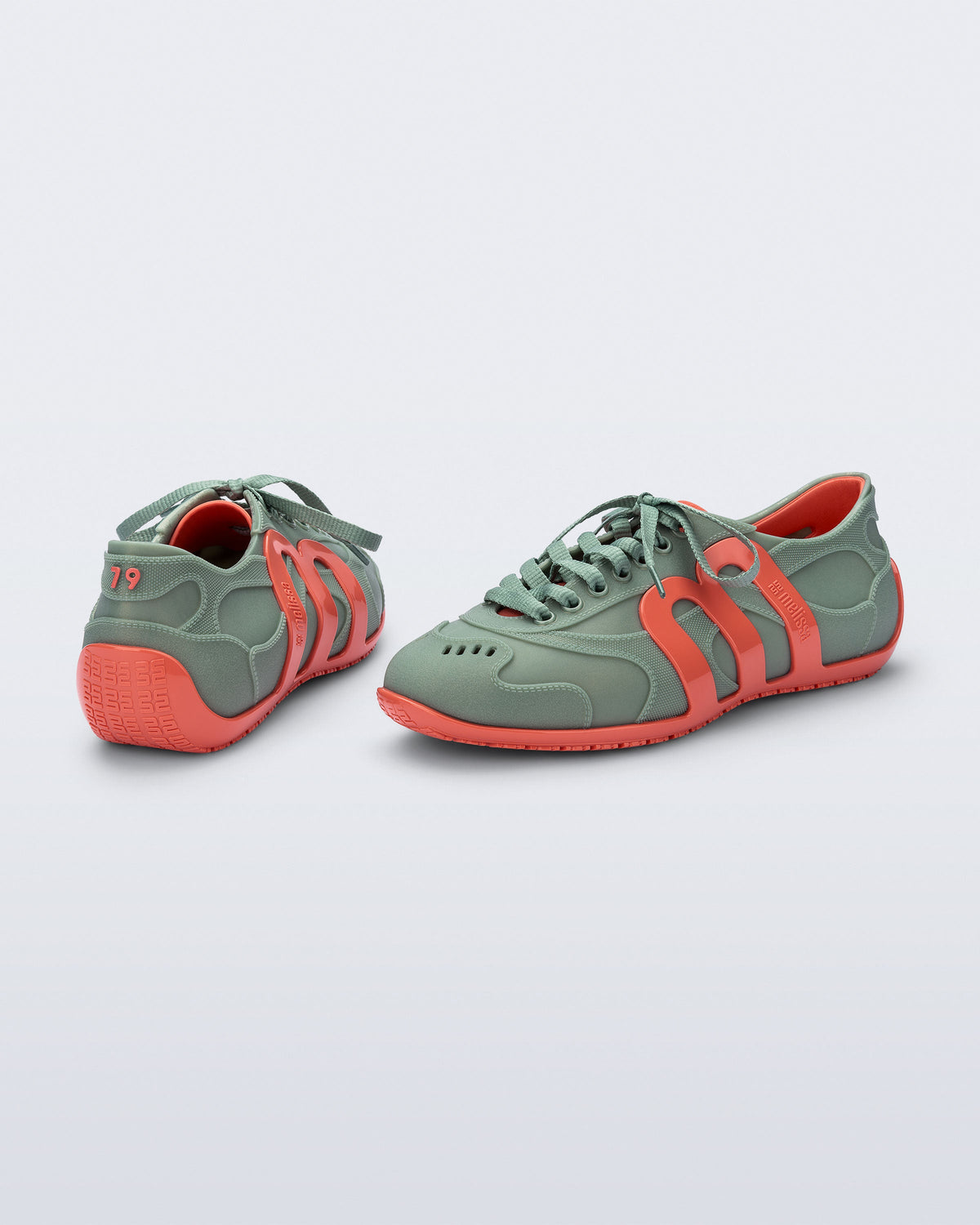 Back and side view of a pair of green Motion sneakers with orange colored sole and M monogram on side and 79 on heel