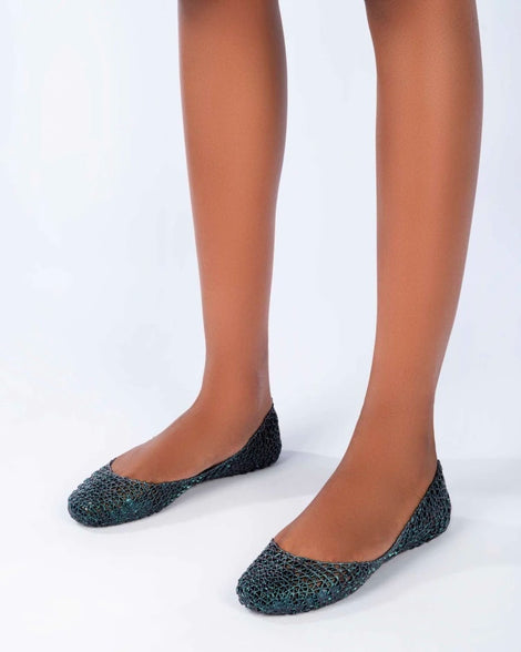 A model's legs wearing a pair of blue Melissa Campana ballet flats.