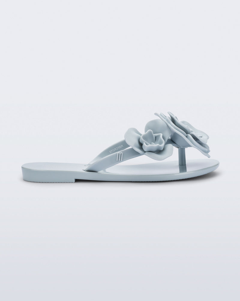 Side view of a blue Harmonic Petals kids flip flop with flowers