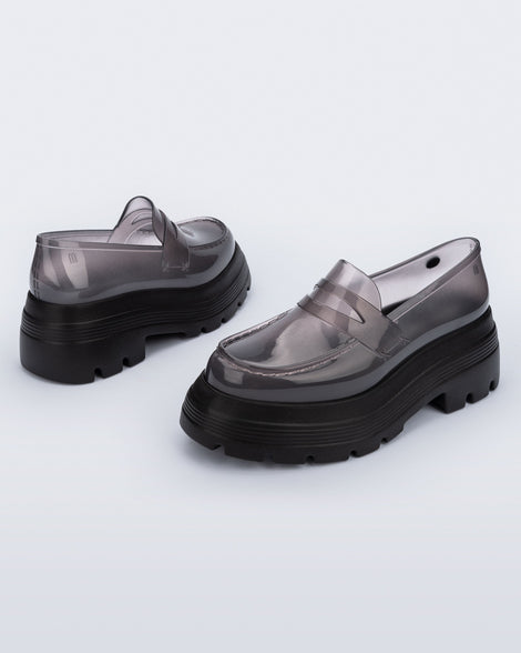 Angled view of a pair of transparent smoke Royal High + Undercover platform loafers with black sole.