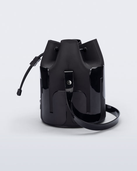 Side view of a Melissa Station bucket bag in Black. The bag has an adjustable shoulder strap and a drawstring top closure.