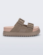 Side view of the melissa cozy platform slide sandal. There are two buckle straps that go across the foot with the M Lover (melissa logo) print embossed into the straps. The buckles are located on the outside edge of the two straps. The straps and platform sole of the shoe are dark beige color and the insole is a lighter color beige.
