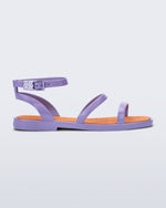 Side view of the Melissa Heat Sandal. This is a flat sandal with a multiple straps, one across the toes, mid part of the foot, and a buckle strap around the ankle with a supporting strap that connects the ankle strap to the sole of the shoe. The straps and outsole are purple and the insole of the shoe is orange. The insole is embossed with a geometric pattern.