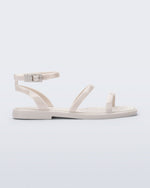 Side view of the Melissa Heat Sandal. This is a flat sandal with a multiple straps, one across the toes, mid part of the foot, and a buckle strap around the ankle with a supporting strap that connects the ankle strap to the sole of the shoe. The straps, insole, outsole, and buckles on the ankle strap are beige. The insole is embossed with a geometric pattern.