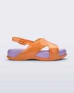 Side view of the Melissa Mare platform sandal. This sandal has two cross straps across the front part of the foot with a thin buckle strap attached. The straps and outsole are orange whiles the platform insole is purple.