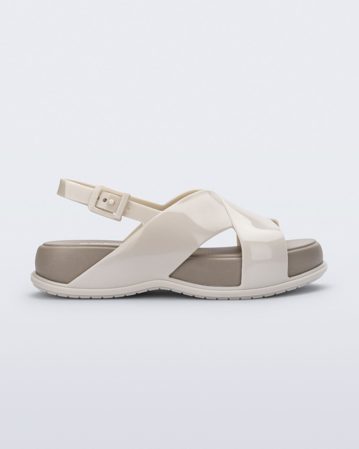 Side view of the Melissa Mare platform sandal. This sandal has two cross straps across the front part of the foot with a thin buckle strap attached. The straps and outsole are light beige while the platform insole is a darker beige.