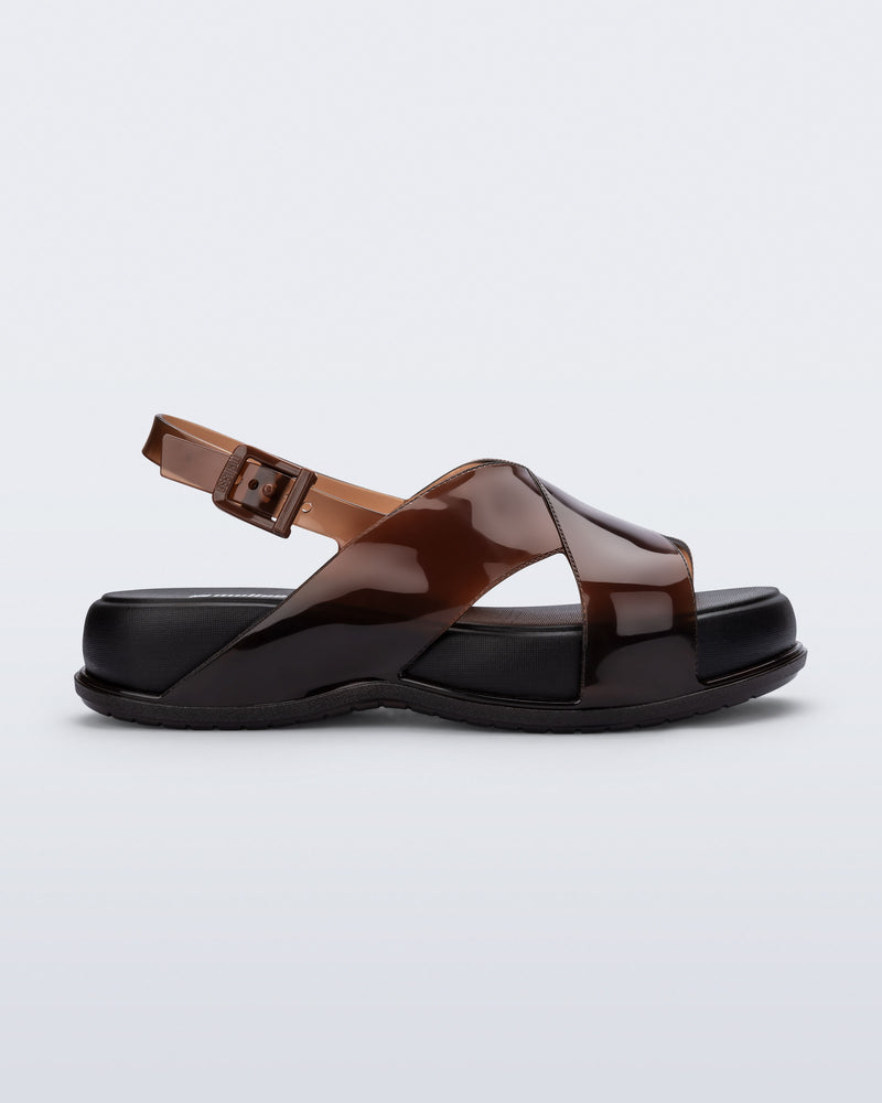 Side view of the Melissa Mare platform sandal. This sandal has two cross straps across the front part of the foot with a thin buckle strap attached. The straps and outsole are brown while the platform insole is black.