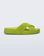 Side view of the Melissa Cozy slide sandals. The slide has two cross straps with Melissa logo embossed onto the straps. The color of the shoe is a lime green.