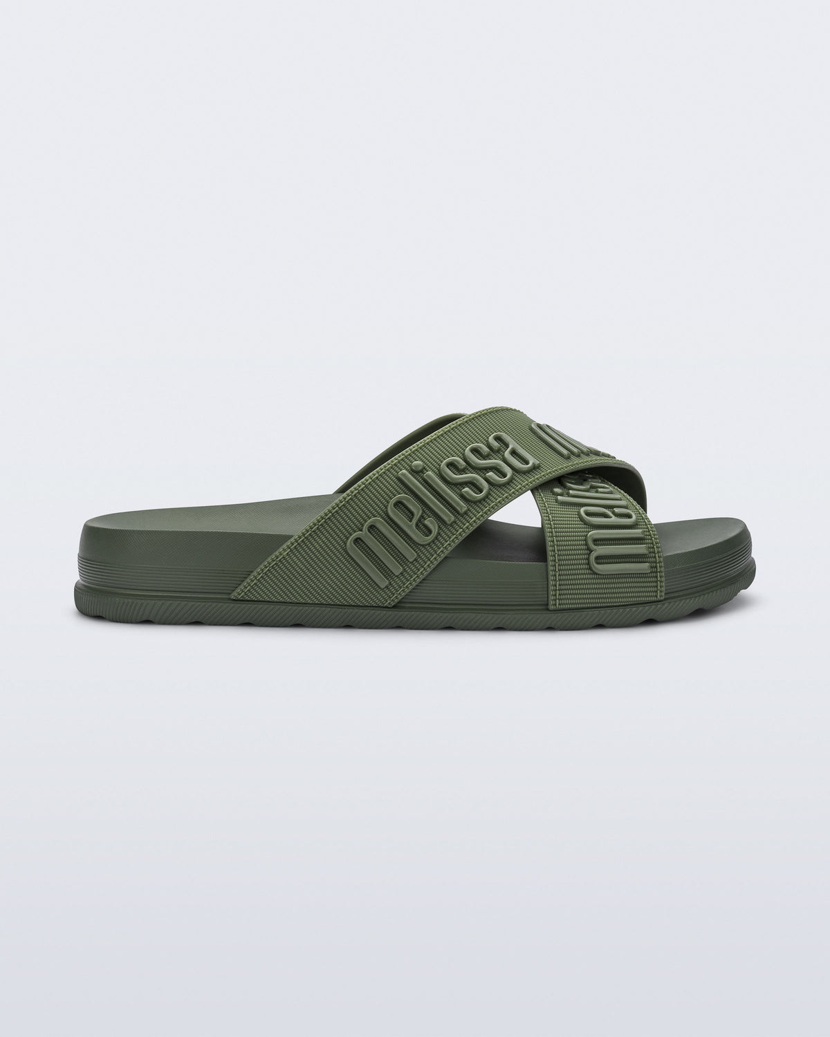 Side view of the Melissa Cozy slide sandals. The slide has two cross straps with Melissa logo embossed onto the straps. The color of the shoe is a dark green.