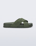 Side view of the Melissa Cozy slide sandals. The slide has two cross straps with Melissa logo embossed onto the straps. The color of the shoe is a dark green.