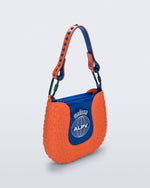 Angled view of an orange Nina Bag + Alexandre Pavao shoulder bag with blue accents