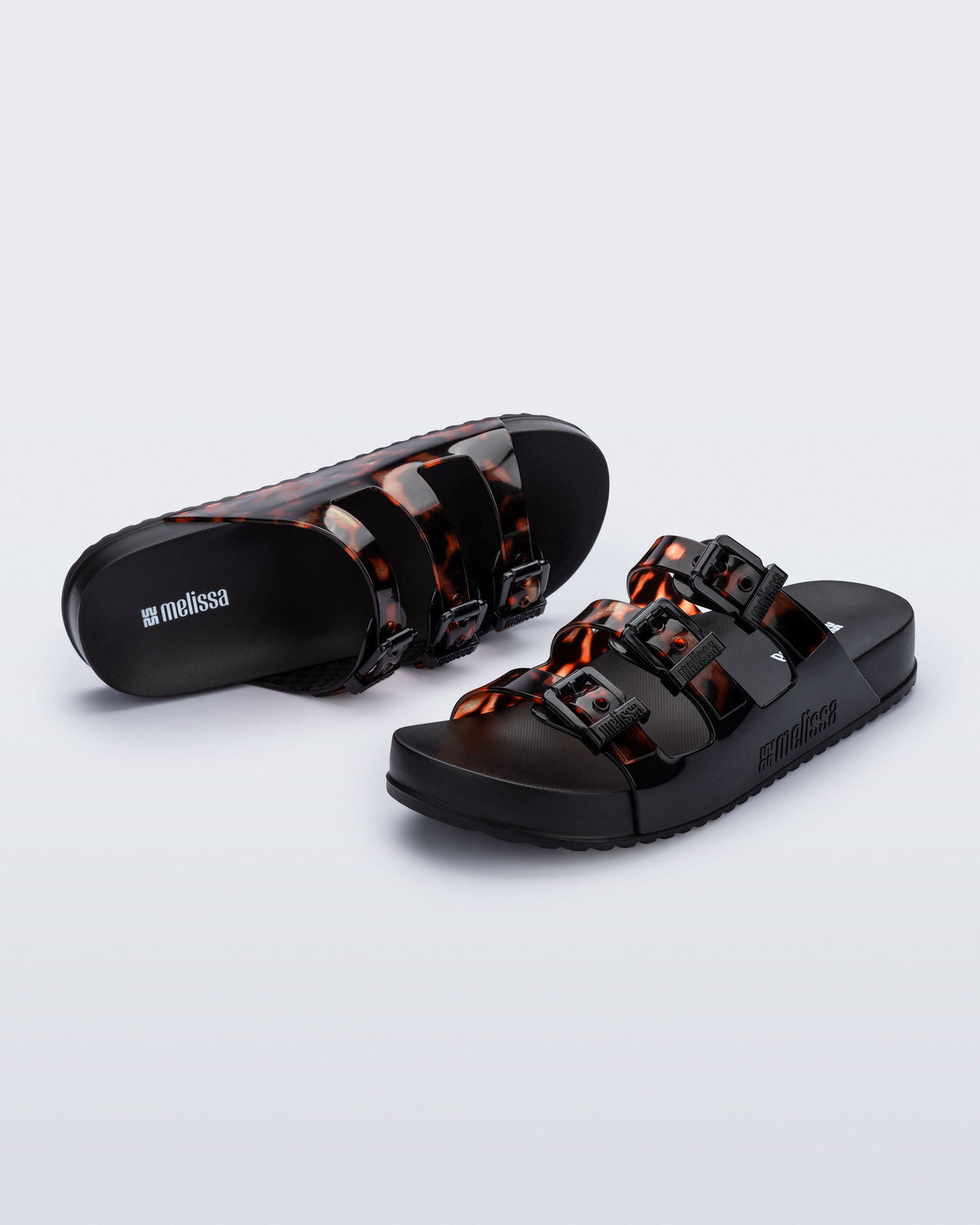 Top and angled view of a pair of black Cozy Stripes slides with tortoise colored straps