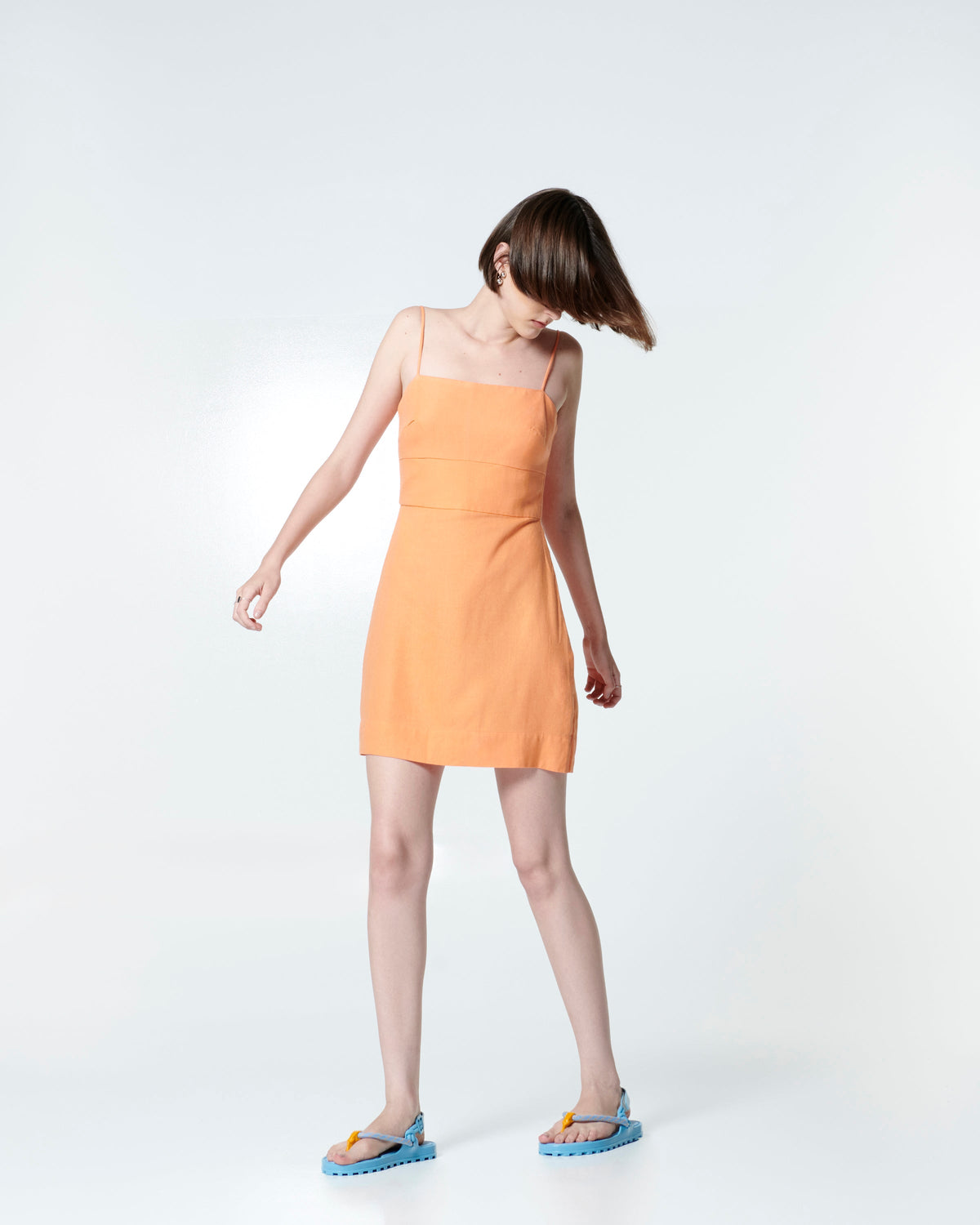 Model in a orange dress wearing a pair of blue Bond sandals with textile strap and orange toe piece