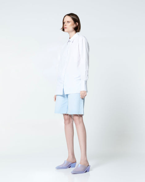 Model in jean shorts and white button down wearing a pair of pearly blue Texas Mule heels