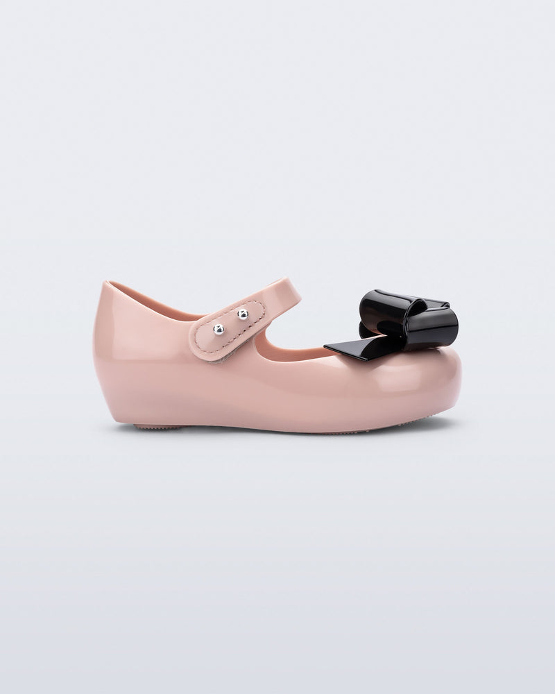 Side view of a pink Ultragirl Classy baby ballerina with black bow.