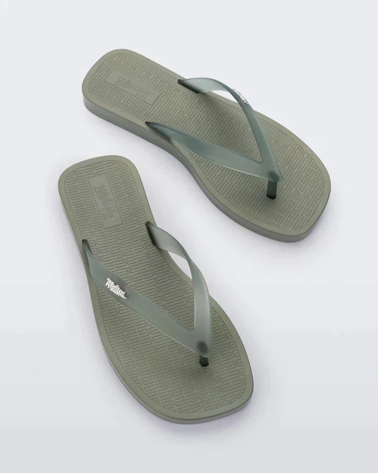 Top view of a pair of green/clear Melissa Sun Long Beach flip flops with a green base and clear green straps with "melissa" on the strap.