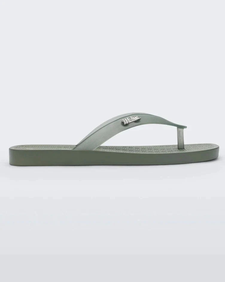 Side view of green/clear Melissa Sun Long Beach flip flop with a green base and clear green straps with "melissa" on the strap.