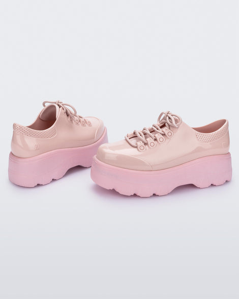 Side view of a pair of pink platform Melissa Kick Off Sneakers with laces.