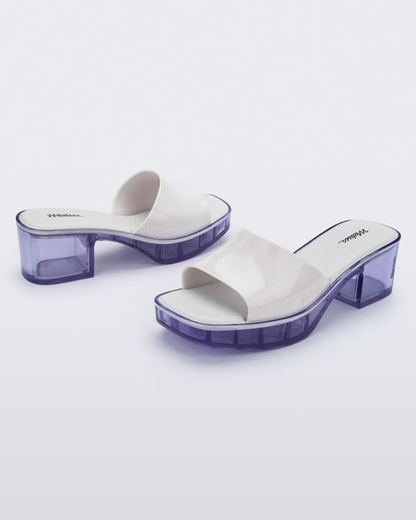 Angled view of a pair of Melissa Shape slides with clear heel and white wide strap