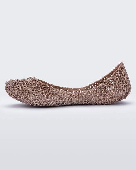 An inner side view of a pink metallic Mini Melissa Campana flat with a woven design base.