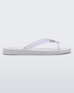 An outter side view of a white/clear Melissa Sun Venice flip flop with a white sole and clear straps with