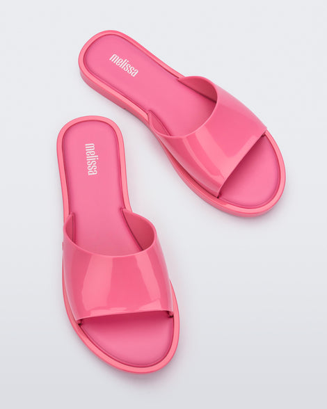 An angled top view of a pair of pink tortoiseshell Melissa Miranda slides