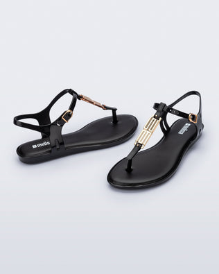 Side and front view of a pair of black Solar M Chic sandals with gold embellishment
