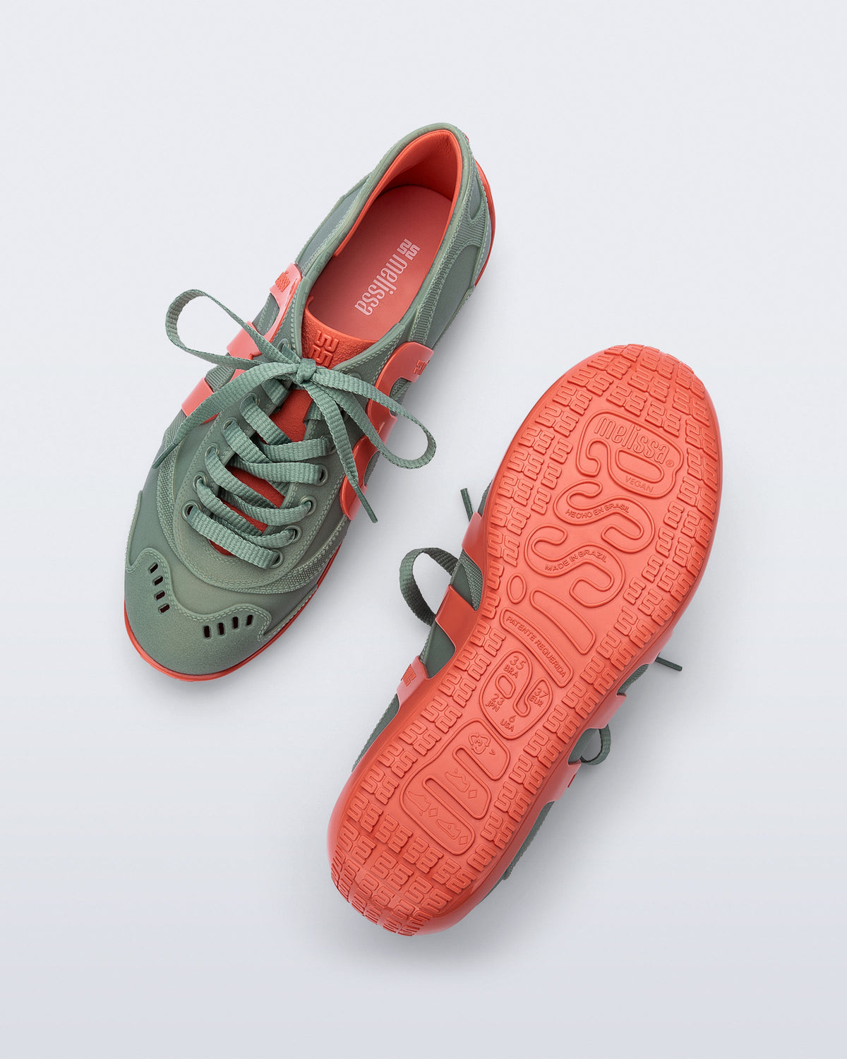Top and bottom view of a pair of green Motion sneakers with orange colored sole and M monogram on side