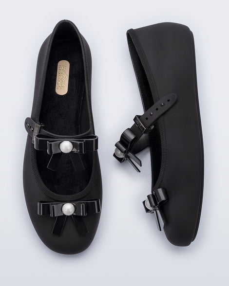 Top and side view of a pair of black Soft Ballerina Bow flats with bows and a pearl in the center of each bow