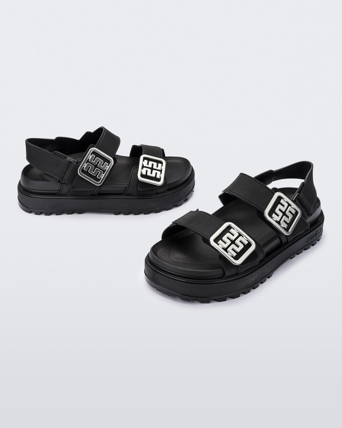 Side and front angled view of a pair of black Towny sandals with straps and silver buckle