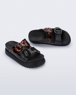 Angled view of a pair of black Cozy Platform sandals with tortoise color straps