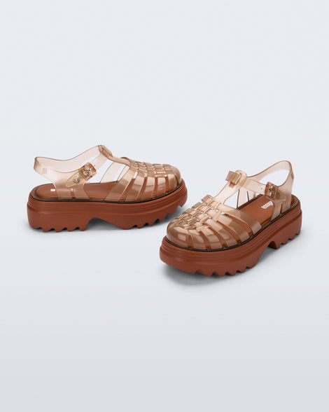 Side and front angled view of a pair of transparent brown Possession Platform II fisherman sandals