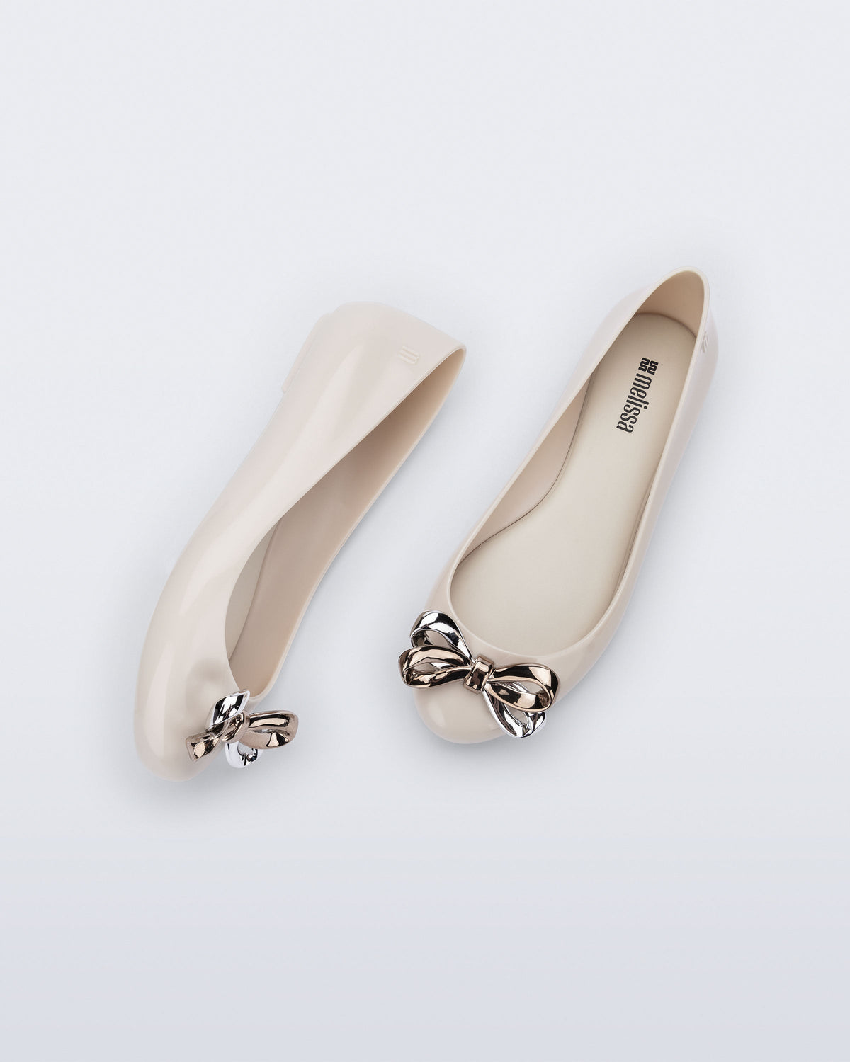 Side and top view of a pair of beige Sweet Love Glam ballerina flats with chrome bow