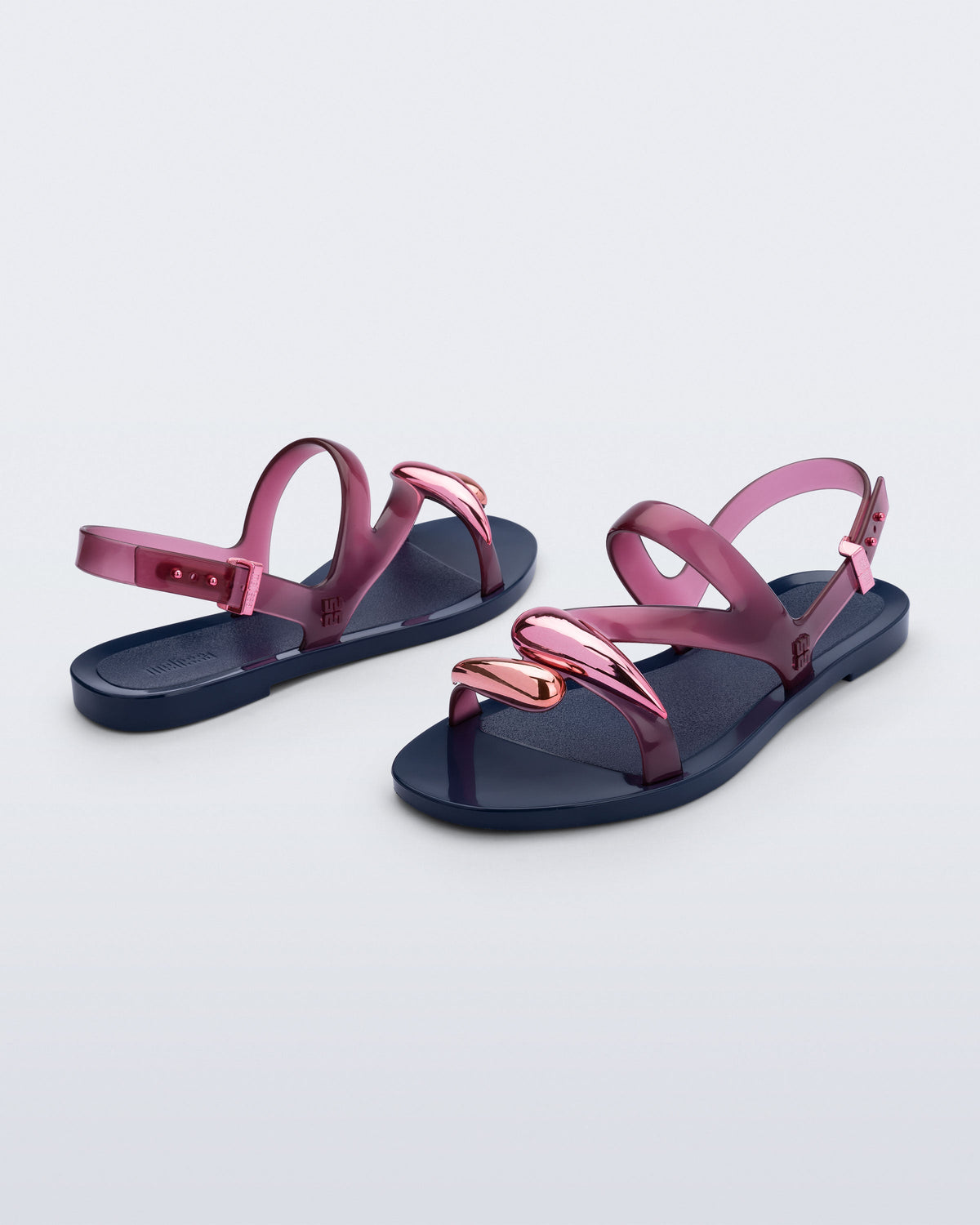 Back and angled view of a pair of pink Iris sandals with blue sole and rose gold upper embellishments