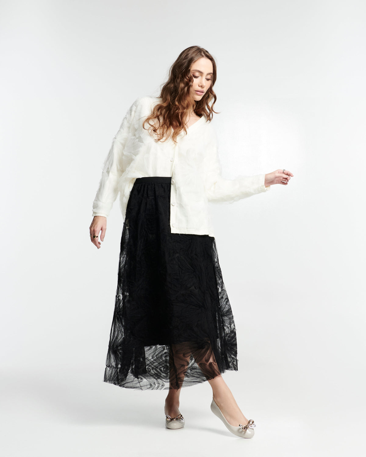 Model in a black skirt and white top wearing a pair of beige Sweet Love Glam ballerina flats with chrome bow