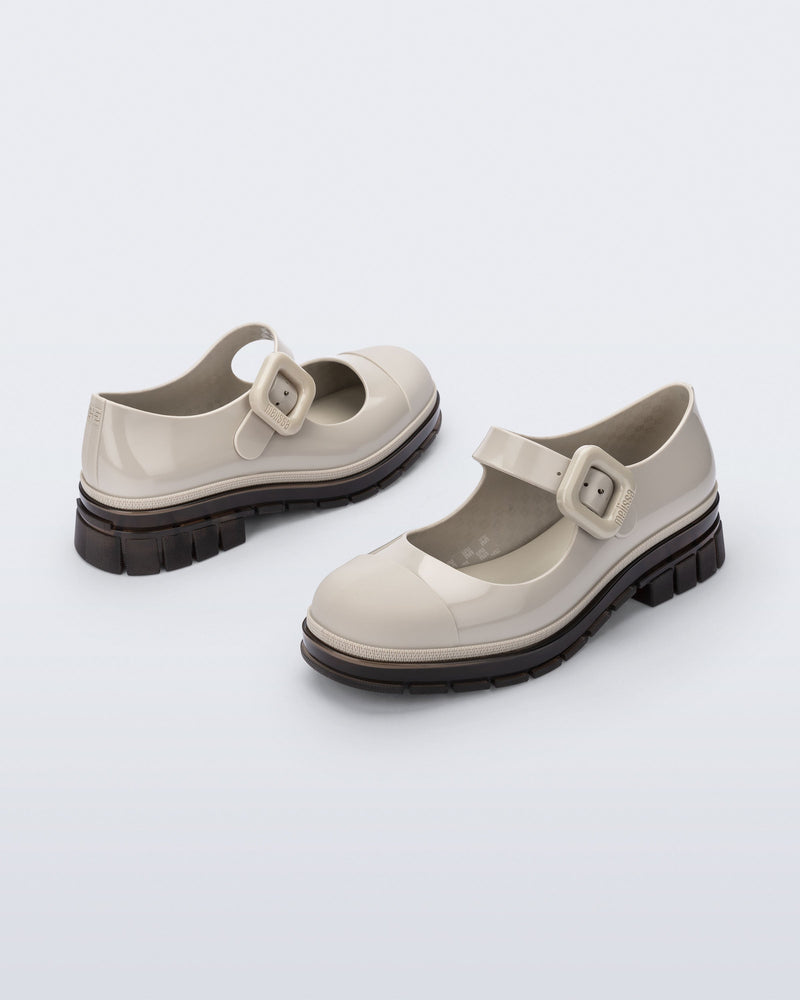 Back and side angle view of a pair of beige with brown sole June mary janes with matte toe cap