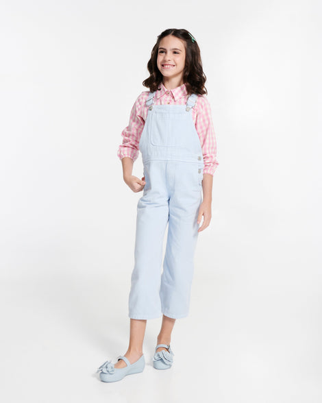 Child model in a blue overalls wearing a pair of blue Soft Ballerina Petals kids flats
