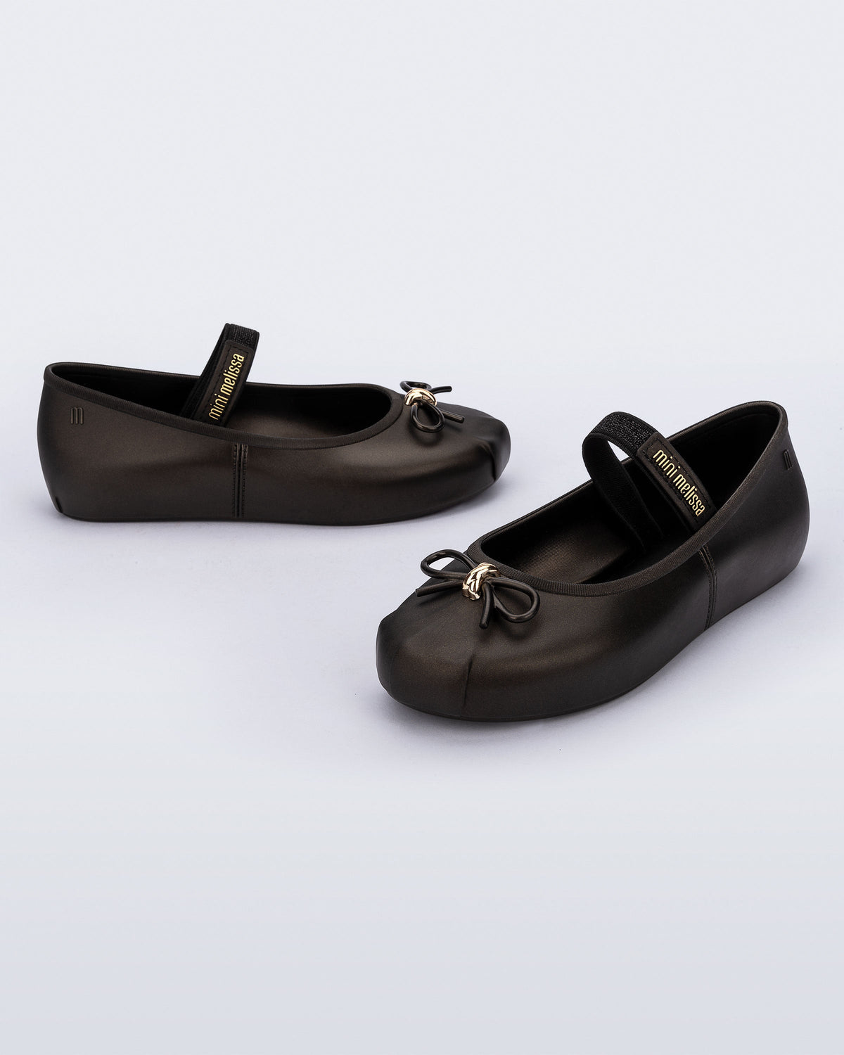 Side and angled view of a pair of metallic black Sophie kids ballerina flats with bow