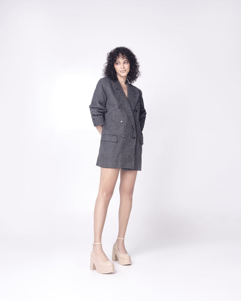 Model in a gray long suit jacket wearing a pair of beige Melissa Doll Heel platforms with ankle strap.