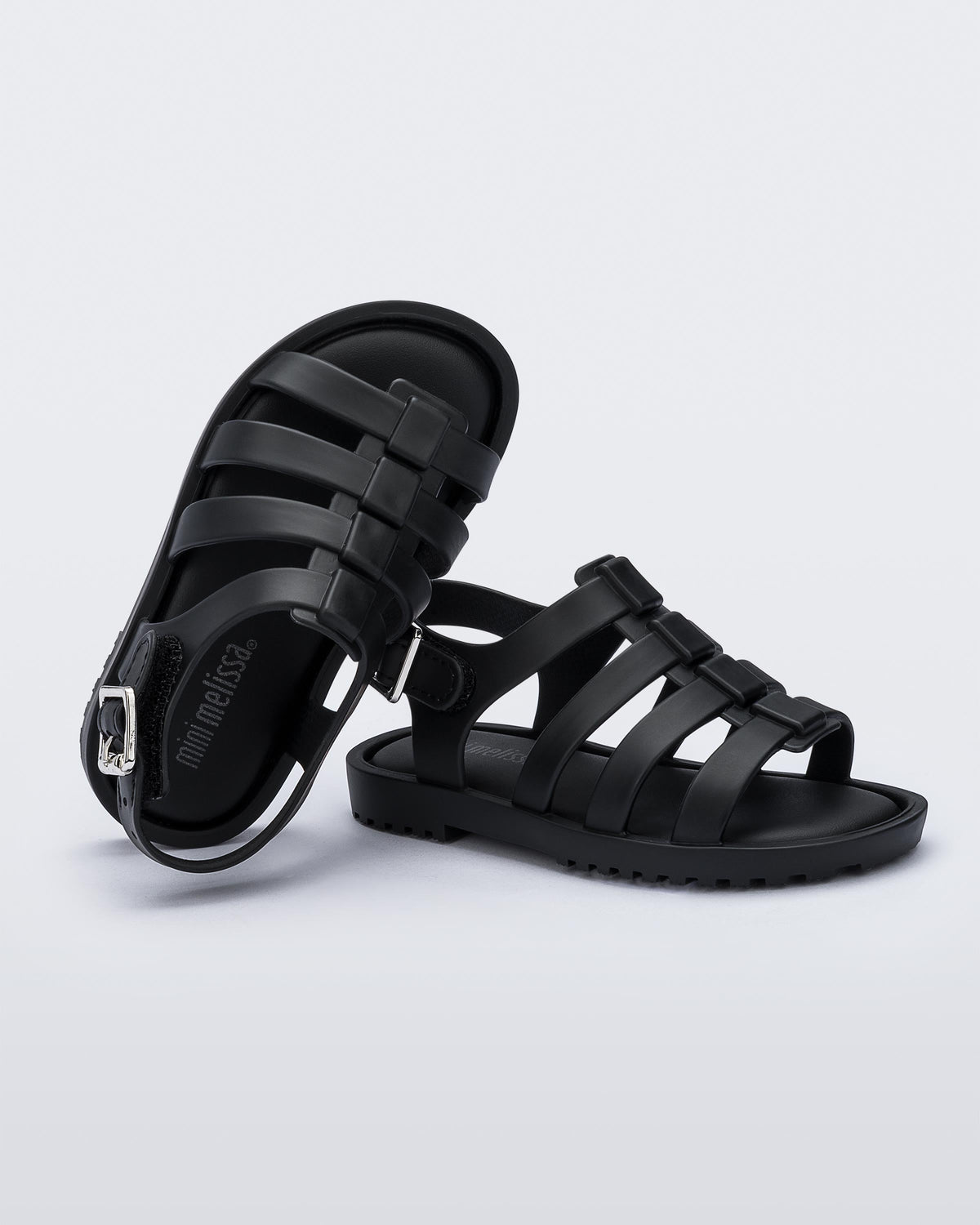 A top and side view of a pair of black Mini Melissa Flox sandals with straps.