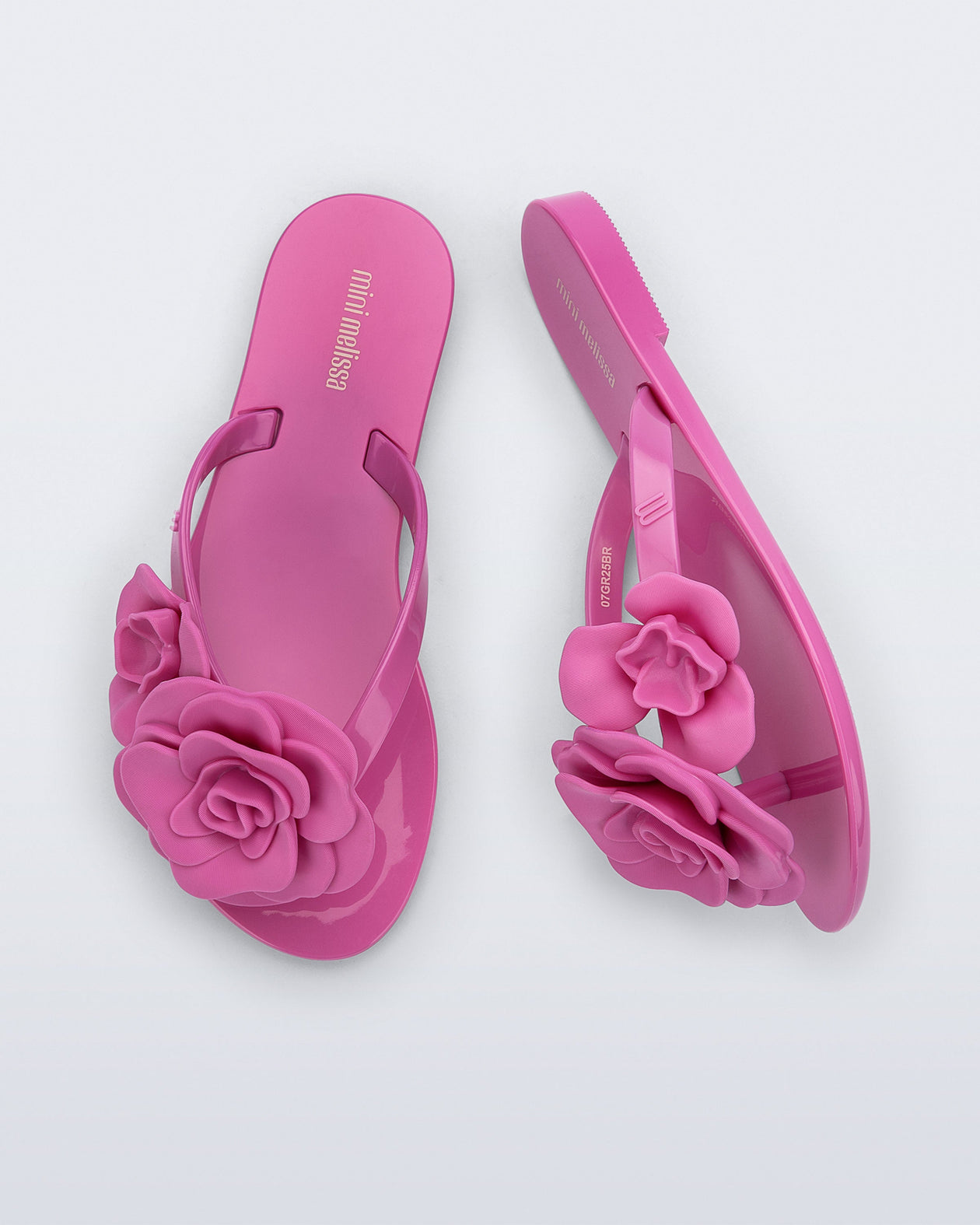 Top and side view of a pair of pink Harmonic Petals kids flip flops with flowers