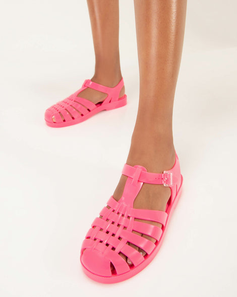 Model's legs in a pair of pink Possession fisherman style sandals.