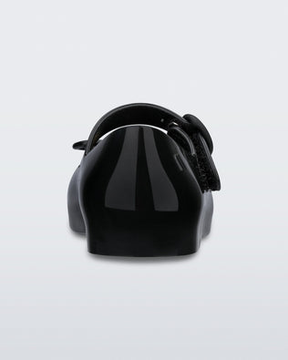 Back view of a black Mini Melissa Sweet Love flat with a top strap and a bow detail on the toe.