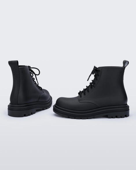 An angled back and side view of a pair of matte black Melissa Coturno boots with a black base, laces and sole.